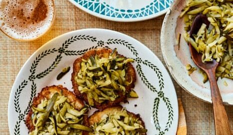 Two plates, each with three servings of courgette kraut, and a serving bowl with a spoon on a brown tablecloth with a chequered tea towel.