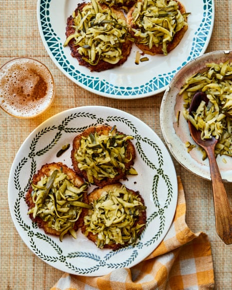 Two plates, each with three servings of courgette kraut, and a serving bowl with a spoon on a brown tablecloth with a chequered tea towel.