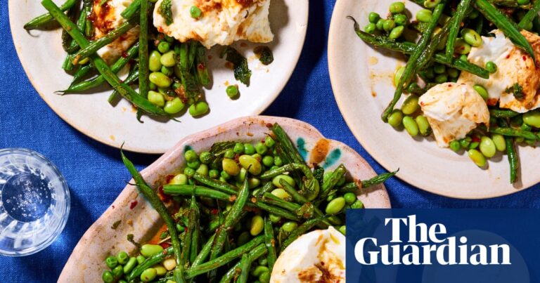 Plates laid out on a table with a blue tablecloth, with the mozzarella and green bean salad on top