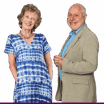 A smiling woman in a blue tie-dye dress and a smiling man in a light coloured suit and shirt
