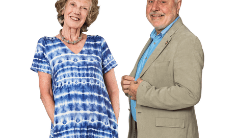 A smiling woman in a blue tie-dye dress and a smiling man in a light coloured suit and shirt