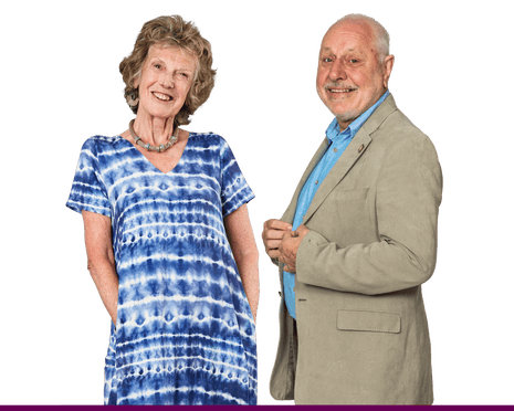 A smiling woman in a blue tie-dye dress and a smiling man in a light coloured suit and shirt