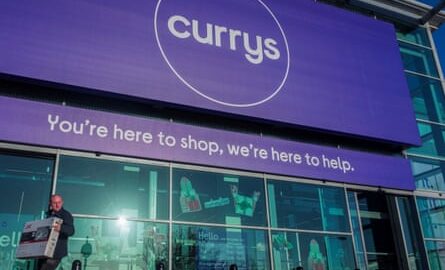 A person carries a television outside a Currys store in London