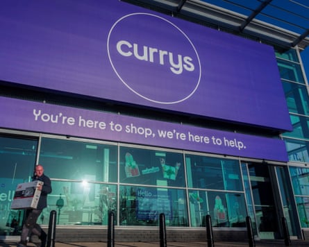 A person carries a television outside a Currys store in London