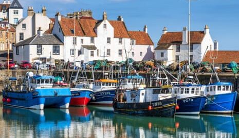 Colourful fishing boats moored in Pittenweem harbour, lined with white-painted stone buildings