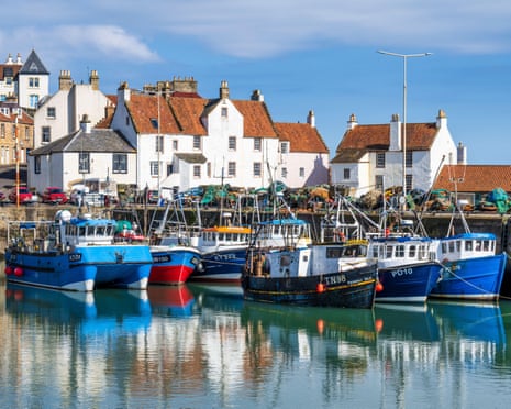 Colourful fishing boats moored in Pittenweem harbour, lined with white-painted stone buildings