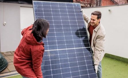 Couple installing a solar panel outdoors