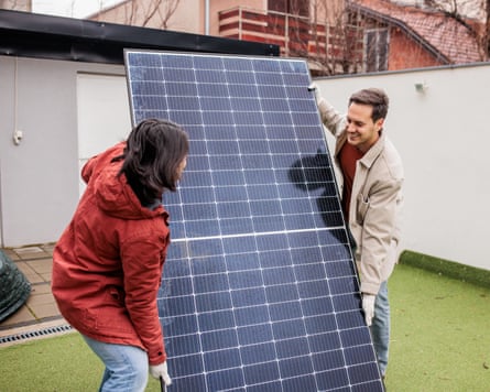 Couple installing a solar panel outdoors