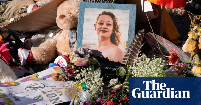 A memorial for Renee Good with flowers, a teddy bear, signs, and her framed photo